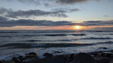 Güney Kaliforniya sahilleri San Diego 'nun kuzeyinde. Sahil şeridi günbatımları, okyanus dalgaları, sörfçüler, gelgit havuzları, palmiye ağaçları ve Encinitas California 'daki Swamis Resif Sörf Parkı' ndaki kaya soyutlamaları..