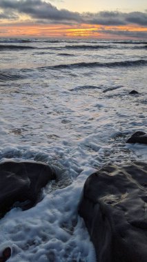 Swamis Sahili 'nde Sunset Sky. Güney Kaliforniya 'nın ücra kumsalları, gün batımları, sörfçüler, gelgit havuzları, dalgalar yontulmuş kayalar, palmiye ağaçları ve San Diego' nun 25 mil kuzeyindeki Encinitas Kayalık Sörf Parkı 'nda şiddetli kış fırtınaları..