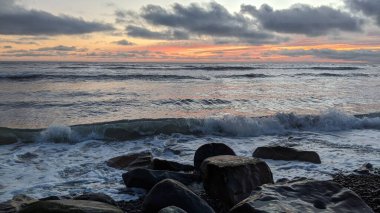 Swamis Sahili 'nde Sunset Sky. Güney Kaliforniya 'nın ücra kumsalları, gün batımları, sörfçüler, gelgit havuzları, dalgalar yontulmuş kayalar, palmiye ağaçları ve San Diego' nun 25 mil kuzeyindeki Encinitas Kayalık Sörf Parkı 'nda şiddetli kış fırtınaları..