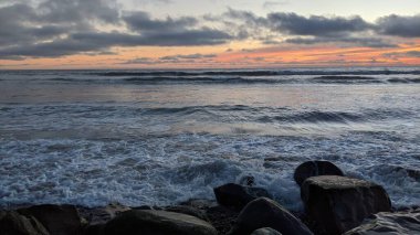 Swamis Sahili 'nde Sunset Sky. Güney Kaliforniya 'nın ücra kumsalları, gün batımları, sörfçüler, gelgit havuzları, dalgalar yontulmuş kayalar, palmiye ağaçları ve San Diego' nun 25 mil kuzeyindeki Encinitas Kayalık Sörf Parkı 'nda şiddetli kış fırtınaları..