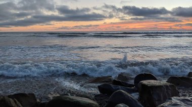 Swamis Sahili 'nde Sunset Sky. Güney Kaliforniya 'nın ücra kumsalları, gün batımları, sörfçüler, gelgit havuzları, dalgalar yontulmuş kayalar, palmiye ağaçları ve San Diego' nun 25 mil kuzeyindeki Encinitas Kayalık Sörf Parkı 'nda şiddetli kış fırtınaları..