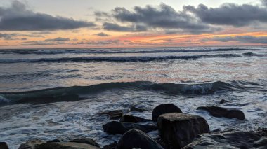 Swamis Sahili 'nde Sunset Sky. Güney Kaliforniya 'nın ücra kumsalları, gün batımları, sörfçüler, gelgit havuzları, dalgalar yontulmuş kayalar, palmiye ağaçları ve San Diego' nun 25 mil kuzeyindeki Encinitas Kayalık Sörf Parkı 'nda şiddetli kış fırtınaları..