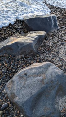 Swamis Sahili 'nin erimiş kayaları sanatı. 50 yıl önce kıyı boyunca uzanan erozyon kontrol kayaları Swamis Resif Parkı Encinitas California 'daki çok renkli nehir kayalarıyla çevrili..