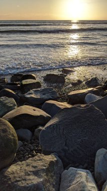 Swamis Sahili 'nin soğuk erimiş kayaları. 50 yıl önce kıyı şeridi boyunca uzanan okyanus dalgası erozyon kontrol taşları şimdi Swamis Resif Sörf Parkı Encinitas California 'daki antik nehir kayalarıyla çevrili soyut heykellere benziyor..