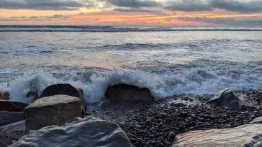 Swamis Sahili 'nin soğuk erimiş kayaları. 50 yıl önce kıyı şeridi boyunca uzanan okyanus dalgası erozyon kontrol taşları şimdi Swamis Resif Sörf Parkı Encinitas California 'daki antik nehir kayalarıyla çevrili soyut heykellere benziyor..