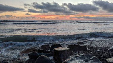 Swamis Sahili 'nde serin renkli River Rocks karışımı. Antik çağlarda hızla yuvarlanan ve parlatılan bu yuvarlak kayalar, Swamis Resif Sörf Parkı Encinitas California 'daki erimiş kayaların heykel ve pürüzsüzleştirilmesine yardımcı oldu..