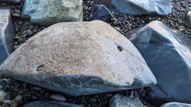 Swamis Sahili 'nde serin renkli River Rocks karışımı. Antik çağlarda hızla yuvarlanan ve parlatılan bu yuvarlak kayalar, Swamis Resif Sörf Parkı Encinitas California 'daki erimiş kayaların heykel ve pürüzsüzleştirilmesine yardımcı oldu..