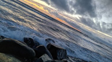 Swamis Sahili 'ndeki Nehir Kayalarının Serin Renkli Karışımı. Antik çağlarda hızla yuvarlanıp parlayan bu yuvarlak kayalar Swamis Resif Sörf Parkı Encinitas California 'daki erimiş kayaların heykelini yaptı..