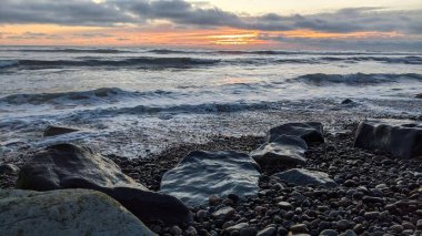 Swamis Sahili 'ndeki Nehir Kayalarının Serin Renkli Karışımı. Antik çağlarda hızla yuvarlanıp parlayan bu yuvarlak kayalar Swamis Resif Sörf Parkı Encinitas California 'daki erimiş kayaların heykelini yaptı..