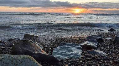 Swamis Sahili 'ndeki Nehir Kayalarının Serin Renkli Karışımı. Antik çağlarda hızla yuvarlanıp parlayan bu yuvarlak kayalar Swamis Resif Sörf Parkı Encinitas California 'daki erimiş kayaların heykelini yaptı..
