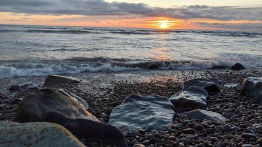 Swamis Sahili 'ndeki Nehir Kayalarının Serin Renkli Karışımı. Antik çağlarda hızla yuvarlanıp parlayan bu yuvarlak kayalar Swamis Resif Sörf Parkı Encinitas California 'daki erimiş kayaların heykelini yaptı..