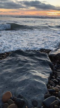 Swamis Sahili 'ndeki Nehir Kayalarının Serin Renkli Karışımı. Antik çağlarda hızla yuvarlanıp parlayan bu yuvarlak kayalar Swamis Resif Sörf Parkı Encinitas California 'daki erimiş kayaların heykelini yaptı..
