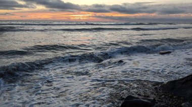 Swamis Sahili 'ndeki Nehir Kayalarının Serin Renkli Karışımı. Antik çağlarda hızla yuvarlanıp parlayan bu yuvarlak kayalar Swamis Resif Sörf Parkı Encinitas California 'daki erimiş kayaların heykelini yaptı..