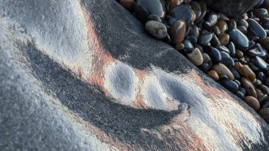 The cool Melted Rocks of Swamis Beach. Ocean wave erosion control quarry rock boulders put down along the shoreline 50 years ago are now resembling abstract sculptures surrounded by ancient river rocks at Swamis Reef Surf Park Encinitas California. clipart