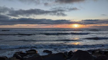 Swamis Sahili 'nde Sunset Sky' dan sonra. Güney Kaliforniya 'nın ücra kumsalları, gün batımları, sörfçüler, gelgit havuzları, dalgalar yontulmuş kayalar, palmiye ağaçları ve San Diego' nun 25 mil kuzeyindeki Encinitas Kayalık Sörf Parkı 'nda şiddetli kış fırtınaları..