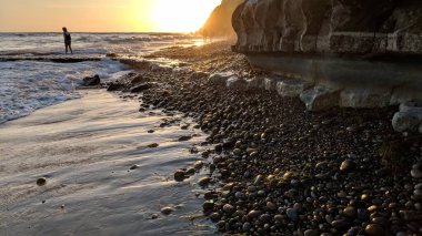 Güney Kaliforniya sahilleri San Diego 'nun kuzeyinde. Sahil şeridi günbatımları, okyanus dalgaları, sörfçüler, gelgit havuzları, palmiye ağaçları ve Encinitas California 'daki Swamis Resif Sörf Parkı' ndaki kaya soyutlamaları..