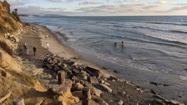 Günbatımı siluetleri, sörfçüleri, gel-git havuzları ve palmiye ağaçları, mavi gökyüzü ve bulutlar ve Encinitas Kaliforniya 'daki Cardiff plajında tatlı dalgalar olan Güney Kaliforniya San Diego kuzey sahneleri..