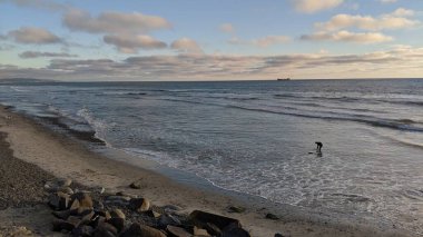 Günbatımı siluetleri, sörfçüleri, gel-git havuzları ve palmiye ağaçları, mavi gökyüzü ve bulutlar ve Encinitas Kaliforniya 'daki Cardiff plajında tatlı dalgalar olan Güney Kaliforniya San Diego kuzey sahneleri..