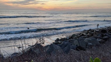 The Cool Colored Mix of River Rocks at Swamis Beach. Rounded and polished from tumbling in ancient fast moving inland streams and ocean waves these round rocks helped sculpture the Melted Rocks at Cardiff and Swamis Reef Parks Encinitas California. clipart