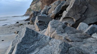 Swamis Sahili 'nin soğuk erimiş kayaları. 50 yıl önce kıyı şeridi boyunca uzanan okyanus dalgası erozyon kontrol taşları şimdi Swamis Resif Sörf Parkı Encinitas California 'daki antik nehir kayalarıyla çevrili soyut heykellere benziyor..