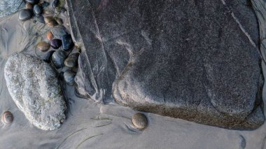 Swamis Sahili 'nin soğuk erimiş kayaları. 50 yıl önce kıyı şeridi boyunca uzanan okyanus dalgası erozyon kontrol taşları şimdi Swamis Resif Sörf Parkı Encinitas California 'daki antik nehir kayalarıyla çevrili soyut heykellere benziyor..