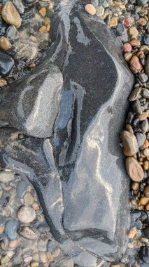 Swamis Sahili 'nin soğuk erimiş kayaları. 50 yıl önce kıyı şeridi boyunca uzanan okyanus dalgası erozyon kontrol taşları şimdi Swamis Resif Sörf Parkı Encinitas California 'daki antik nehir kayalarıyla çevrili soyut heykellere benziyor..