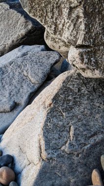 Swamis Sahili 'nin erimiş kayaları sanatı. 50 yıl önce kıyı boyunca uzanan erozyon kontrol kayaları Swamis Resif Sörf Parkı Encinitas California 'daki dalga enerjili kaya parlatıcı ekibindeki çok renkli nehir kayalarıyla çevrili..