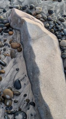 Swamis Sahili 'nin erimiş kayaları sanatı. 50 yıl önce kıyı boyunca uzanan erozyon kontrol kayaları Swamis Resif Sörf Parkı Encinitas California 'daki dalga enerjili kaya parlatıcı ekibindeki çok renkli nehir kayalarıyla çevrili..