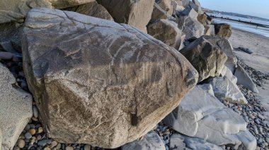 Swamis Sahili 'nin erimiş kayaları sanatı. 50 yıl önce kıyıya bırakılan erozyon kontrol kayaları şu anda çok renkli nehir kayalarıyla çevrili. Swamis Resif Sörf Parkı Encinitas California 'da tüm okyanus dalgaları parlıyor..