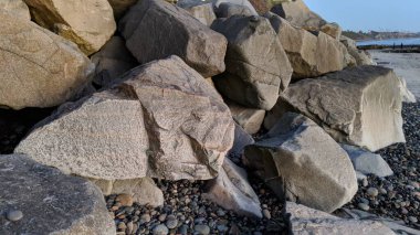 Swamis Sahili 'nin erimiş kayaları sanatı. 50 yıl önce kıyıya bırakılan erozyon kontrol kayaları şu anda çok renkli nehir kayalarıyla çevrili. Swamis Resif Sörf Parkı Encinitas California 'da tüm okyanus dalgaları parlıyor..