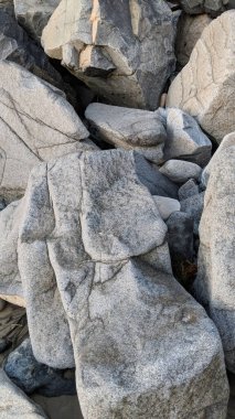 Swamis Sahili 'nin erimiş kayaları sanatı. 50 yıl önce kıyı boyunca uzanan erozyon kontrol kayaları Swamis Resif Sörf Parkı Encinitas California 'daki dalga enerjili kaya parlatıcı ekibindeki çok renkli nehir kayalarıyla çevrili..