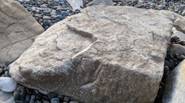 Swamis Sahili 'nin erimiş kayaları sanatı. 50 yıl önce kıyı boyunca uzanan erozyon kontrol kayaları Swamis Resif Sörf Parkı Encinitas California 'daki dalga enerjili kaya parlatıcı ekibindeki çok renkli nehir kayalarıyla çevrili..