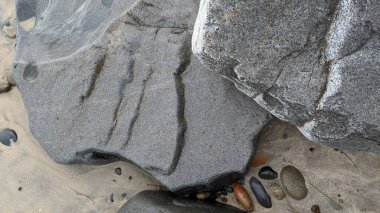 Swamis Sahili 'nin serin erimiş kayalıkları. 50 yıl önce, Swamis Resif Parkı Encinitas 'taki Swamis Sörf Parkı Encinitas' ta sörf yapan kayalar tarafından çevrelenmiş eski nehir kayalarıyla çevrelenmiş erozyon kontrol kayaları..