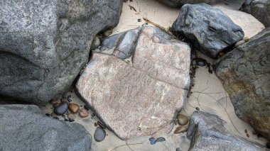 Swamis Sahili 'nin soğuk erimiş kayaları. 50 yıl önce, Swamis Resif Parkı Encinitas 'taki Swamis Sörf Parkı Encinitas' ta sörf yapan kayalar tarafından çevrelenmiş eski nehir kayalarıyla çevrelenmiş erozyon kontrol kayaları..