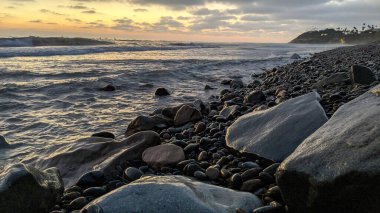 Swamis Sahili 'nin soğuk erimiş kayaları. 50 yıl önce, Swamis Resif Parkı Encinitas 'taki Swamis Sörf Parkı Encinitas' ta sörf yapan kayalar tarafından çevrelenmiş eski nehir kayalarıyla çevrelenmiş erozyon kontrol kayaları..