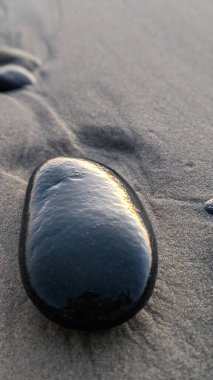 The abstract Melted Rocks of Swamis Beach. Erosion control boulders put down along the shore 50 years ago surrounded by ancient river rocks all together in the surf mix at Swamis Reef Surf Park Encinitas California. clipart