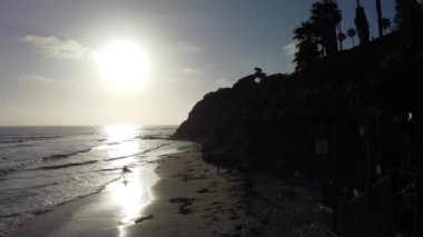 Günbatımı siluetleri, sörfçüleri, gelgit havuzları ve palmiye ağaçlarıyla Encinitas California 'daki Swamis Resif Sörf Parkı' nda güneşli Güney Kaliforniya sahneleri..