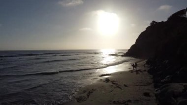 Günbatımı siluetleri, sörfçüleri, gelgit havuzları ve palmiye ağaçlarıyla Encinitas California 'daki Swamis Resif Sörf Parkı' nda güneşli Güney Kaliforniya sahneleri..