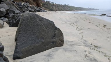 Swamis Sahili 'nin Erimiş Kayalıkları. 50 yıl önce kıyı boyunca uzanan erozyon kontrol kayaları Swamis Resif Sörf Parkı Encinitas California 'daki dalga enerjili kaya parlatıcı ekibindeki çok renkli nehir kayalarıyla çevrili..