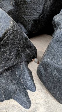 Swamis Sahili 'nin Erimiş Kayalıkları. 50 yıl önce kıyı boyunca uzanan erozyon kontrol kayaları Swamis Resif Sörf Parkı Encinitas California 'daki dalga enerjili kaya parlatıcı ekibindeki çok renkli nehir kayalarıyla çevrili..