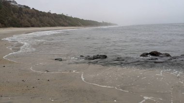 Güney Kaliforniya 'da gizli plajlar, gün batımları, sörfçüler, gelgit havuzları, sahil kayalıkları, palmiye ağaçları ve San Diego' nun 25 mil kuzeyindeki Encinitas kıyılarındaki Swamis Kayalık Sörf Parkı 'nda şiddetli kış fırtınaları..