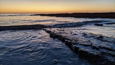 Günbatımında Güney Kaliforniya sahillerinde, eski resif gel-git havuzları, okyanus dalgaları ve Swamis Resif Parkı Encinitas California 'da alacakaranlık renkli gökyüzü.