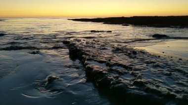 Günbatımında Güney Kaliforniya sahillerinde, eski resif gelgitleri, okyanus dalgaları ve karanlık gökyüzü Swamis Resif Parkı Encinitas California 'da..