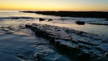 Günbatımında Güney Kaliforniya sahillerinde, eski resif gelgitleri, okyanus dalgaları ve karanlık gökyüzü Swamis Resif Parkı Encinitas California 'da..