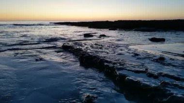 Günbatımında Güney Kaliforniya sahillerinde, eski resif gelgitleri, okyanus dalgaları ve karanlık gökyüzü Swamis Resif Parkı Encinitas California 'da..