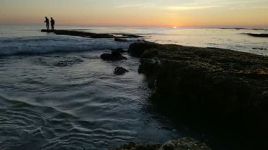 Günbatımında Güney Kaliforniya sahillerinde, eski resif gelgitleri, okyanus dalgaları ve karanlık gökyüzü Swamis Resif Parkı Encinitas California 'da..