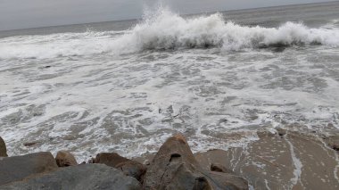 Swamis Sahili 'nin Erimiş Kayalıkları. Okyanus dalgası erozyon kontrol taşları 50 yıl önce kıyı şeridi boyunca uzanan kaya parçaları şimdi Swamis Resif Sörf Parkı Encinitas California 'daki antik nehir kayalarıyla çevrili soyut heykellere benziyor..