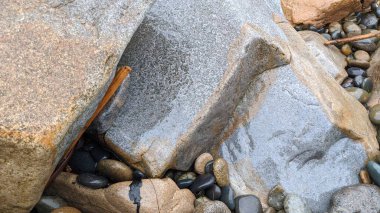 Erimiş kayalar ve Swamis Sahili 'nin kayalıkları. 50 yıl önce kıyıya bırakılan erozyon kontrol kayaları Swamis Resif Sörf Parkı Encinitas California 'daki dalgaların karışımında eski nehir kayalarıyla çevrili dalgalarla aşınmış..