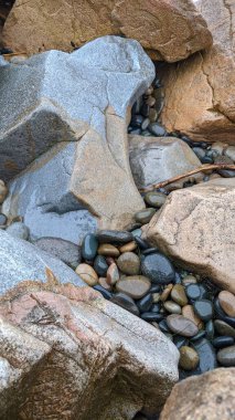 Erimiş kayalar ve Swamis Sahili 'nin kayalıkları. 50 yıl önce kıyıya bırakılan erozyon kontrol kayaları Swamis Resif Sörf Parkı Encinitas California 'daki dalgaların karışımında eski nehir kayalarıyla çevrili dalgalarla aşınmış..