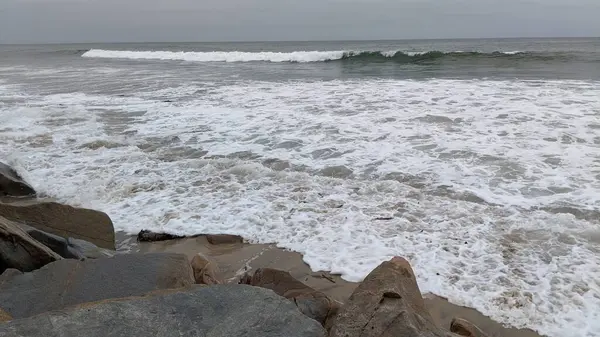 Swamis Sahili 'nin Erimiş Kayalıkları. Okyanus dalgası erozyon kontrol taşları 50 yıl önce kıyı şeridi boyunca uzanan kaya parçaları şimdi Swamis Resif Sörf Parkı Encinitas California 'daki antik nehir kayalarıyla çevrili soyut heykellere benziyor..